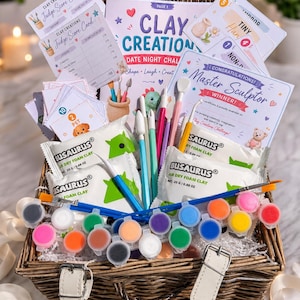 May include: A wicker basket containing a Clay Creations date night challenge kit with score cards, a Master Sculptor certificate, sculpting tools, paint brushes, multiple small paint pots in various colours, and packets of Busaurus air dry foam clay.
