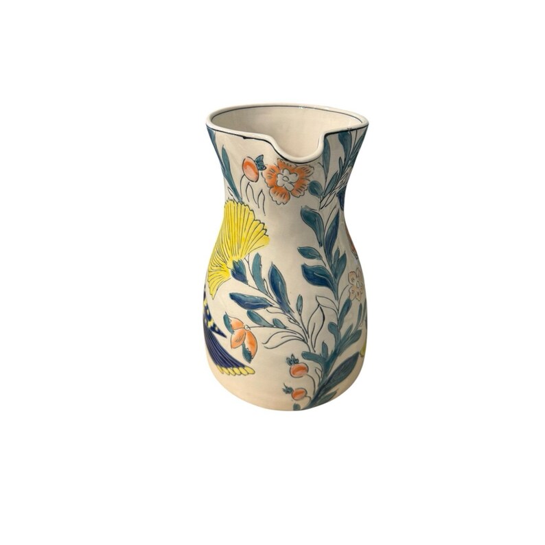 May include: A ceramic pitcher with a cream-colored base, adorned with a floral pattern in yellow, orange, and blue. The pitcher has a spout and a wide opening, suitable for serving beverages. The design includes stylized flowers and leaves.