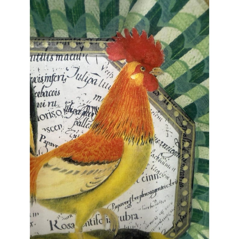 May include: A colorful illustration of a rooster with a red comb and orange and yellow feathers. The rooster is positioned in front of a decorative frame with handwritten text. The background features a green and white geometric pattern.