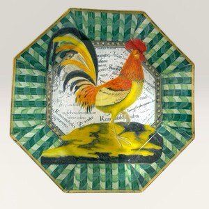 May include: An octagonal decorative plate featuring a rooster illustration. The rooster has red, orange, and yellow feathers, standing on a yellow base. The plate has a green and white checkered border with gold trim.