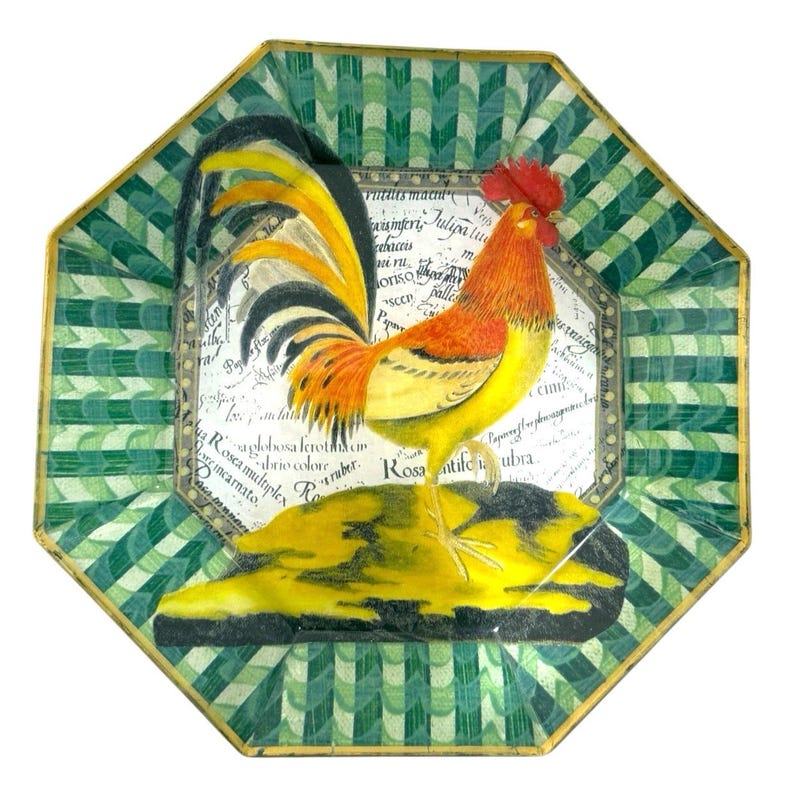 May include: An octagonal decorative plate featuring a colorful rooster illustration. The rooster has orange, yellow, and black feathers, standing on a yellow base. The plate has a green and white geometric border and text in the center.