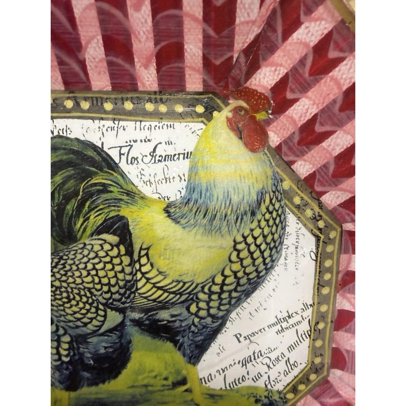 May include: A decorative image featuring a detailed illustration of a rooster with yellow, black, and blue plumage, a red comb, and wattle. The rooster is set against a white background with script and a gold-colored frame. The background is a red and white checkered pattern.