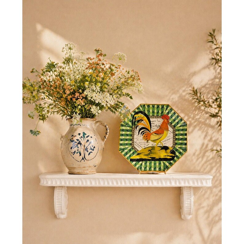 May include: A decorative shelf displays a floral arrangement in a ceramic vase and a decorative plate. The plate features a rooster design with green, yellow, and red accents. The vase has a blue and white floral pattern.