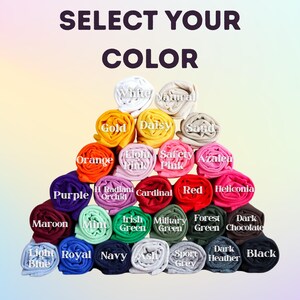 Op de afbeelding: Een piramide van opgerolde stof in verschillende kleuren, waaronder wit, goud, oranje, paars, rood en zwart. Elke rol is gelabeld met zijn kleurnaam, zoals "Wit", "Goud" en "Zwart". De tekst "SELECT YOUR COLOR" staat bovenaan.