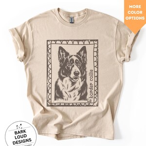 Könnte beinhalten: Beiges T-Shirt mit einer detaillierten Illustration eines Border Collie-Hundes in einem dekorativen Rahmen. Der Text "border collie" ist vertikal auf der rechten Seite des Rahmens aufgedruckt. Das Shirt hat auch den Text "Bark Loud Designs by Nadine Mehmet" in einem kreisförmigen Logo.