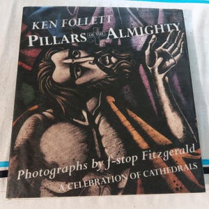 Könnte beinhalten: Buchcover von "Pillars of the Almighty" von Ken Follett. Es zeigt eine Illustration einer Person, die nach oben blickt. Der Text "Photographs by f-stop Fitzgerald" und "A Celebration of Cathedrals" sind ebenfalls zu sehen.