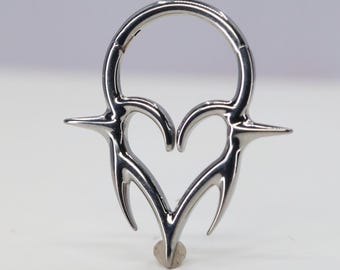 May include: A silver-coloured, heart-shaped, body jewellery piece with a circular ring at the top and a pointed design at the bottom.