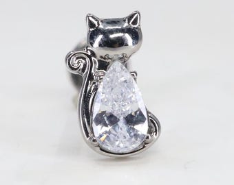 Peut inclure: Un charme de chat en argent avec un cristal clair en forme de poire. Le chat est assis avec sa queue enroulée autour de son corps.