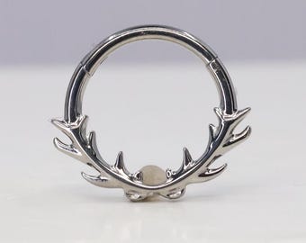 Peut inclure: Un anneau circulaire segmenté argenté avec un motif d'antenne décoratif. L'anneau est en acier chirurgical et convient au piercing corporel.