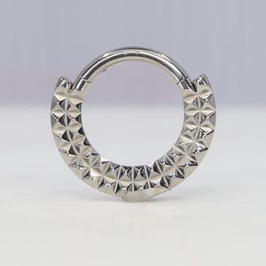 May include: A silver seamless ring with a textured diamond pattern around the entire circumference.