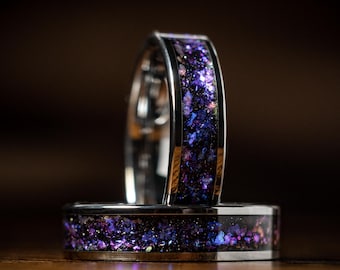 May include: Two silver rings with a purple and blue glitter inlay. The rings are stacked on top of each other.