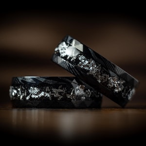 May include: Two black and silver rings with a textured finish. The rings are stacked on top of each other.