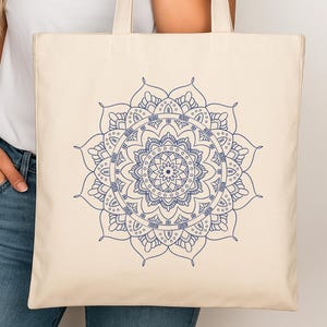 May include: A white canvas tote bag with a blue mandala design. The bag has two long handles.