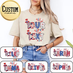 May include: A beige short-sleeve t-shirt featuring a patriotic graphic design with the text YOUR TEXT in large letters filled with red, white, and blue patterns, accented by fireworks and small top hats. The design includes stars and stripes motifs.