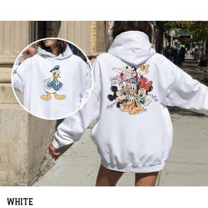 May include: White hooded sweatshirt featuring Donald Duck on the front and a group of Disney characters on the back. The Donald Duck graphic shows him in a blue sailor suit. The back graphic includes Mickey Mouse, Minnie Mouse, and Pluto.
