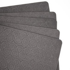 May include: A stack of six black foam sheets with a repeating pattern of circles and swirls.