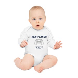 May include: White baby onesie with a blue graphic of a video game controller and the text "NEW PLAYER" and "LOADING" with a progress bar of hearts.