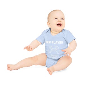 May include: A baby wearing a light blue bodysuit with the text "NEW PLAYER" and a graphic of a video game controller. The text "LOADING..." is below the controller graphic.