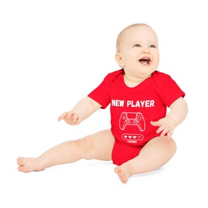 May include: A red baby onesie with a white graphic of a video game controller and the text "NEW PLAYER" with a loading bar and hearts.