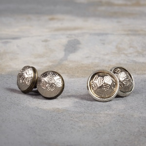May include: A set of four silver-toned metal buttons with a textured design. The buttons have a raised, circular pattern and a slightly darker rim.