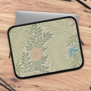 Könnte beinhalten: Eine Laptop-Hülle mit einem floralen Muster mit grünen Blättern, rosa und weißen Blüten sowie blauen Blüten. Die Hülle hat einen Reißverschluss.