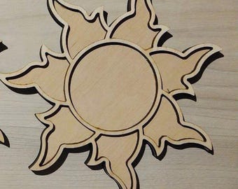 May include: Wooden sunburst shape with a circular center and pointed rays. The sunburst is made of light-colored wood with dark brown outlines, creating a contrasting effect. The design is likely for decorative purposes.