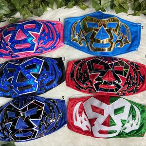 K&ouml;nnte beinhalten: Sechs verschiedene Wrestling-Masken, jede mit einem einzigartigen Design und Farbschema. Die Masken sind aus Stoff und haben ein schwarz-wei&szlig;es Sch&auml;del-Design mit verschiedenen farbigen Akzenten. Die Masken sind von 1 bis 6 nummeriert.