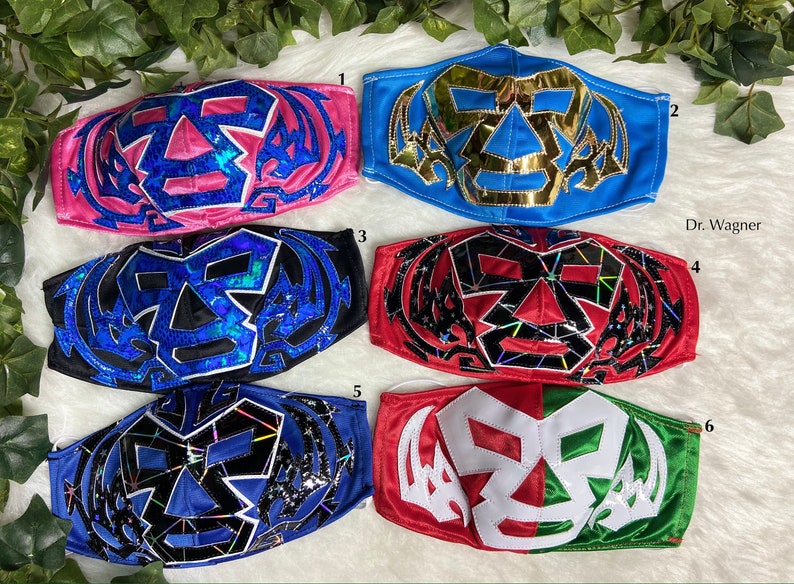 K&ouml;nnte beinhalten: Sechs verschiedene Wrestling-Masken, jede mit einem einzigartigen Design und Farbschema. Die Masken sind aus Stoff und haben ein schwarz-wei&szlig;es Sch&auml;del-Design mit verschiedenen farbigen Akzenten. Die Masken sind von 1 bis 6 nummeriert.
