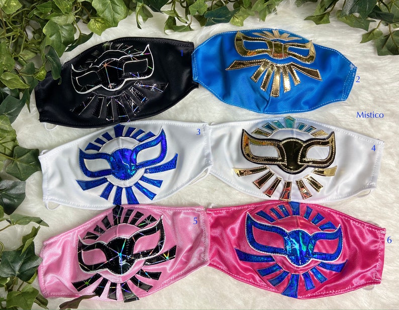 K&ouml;nnte beinhalten: Sechs Luchador-Masken in verschiedenen Farben. Die Masken sind aus Stoff und haben ein goldenes, blaues oder schwarzes Design. Die Masken sind von 1 bis 6 nummeriert.
