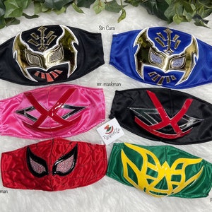 K&ouml;nnte beinhalten: Sechs bunte Stoffmasken mit verschiedenen Wrestling-Charakterdesigns. Die Masken sind schwarz, blau, rosa, rot, gr&uuml;n und gelb. Die Masken haben verschiedene Designs, darunter einen Sch&auml;del, eine Spinne und einen Fisch.