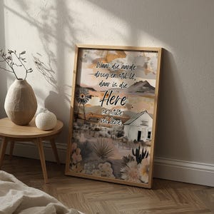 May include: A framed landscape art print with a wooden frame. The artwork depicts a rural scene with a windmill, a small house, and text that reads "Waar die aarde droog en stil lê, daar is die Here se stilte vol lewe."