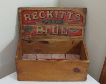 May include: Wooden box with the words "RECKITT'S PARIS BLUE" in red and gold lettering. The box contains several small blue and red boxes. The wood has a natural finish.