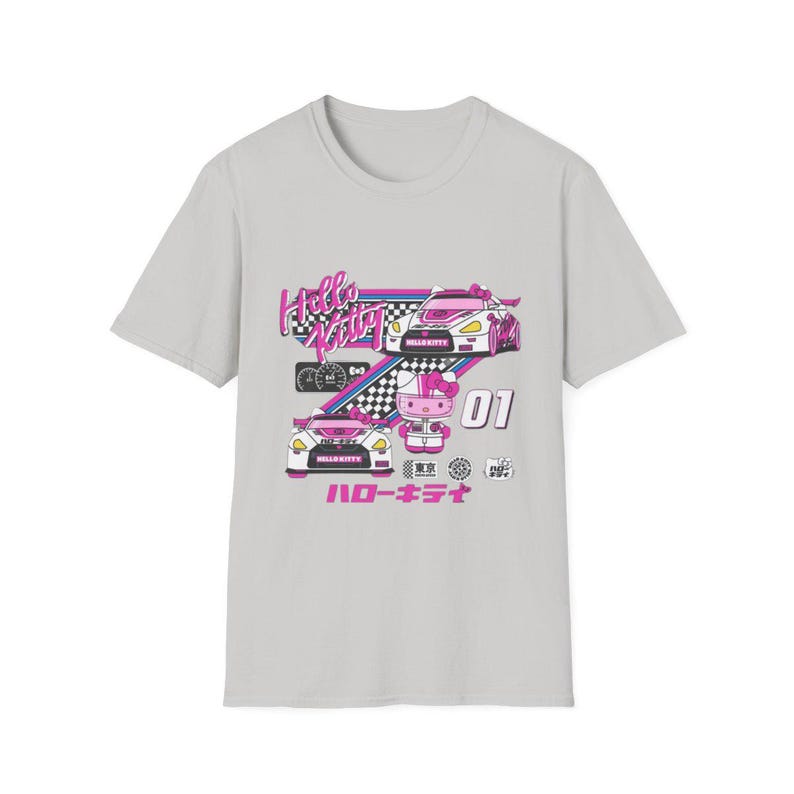 Op de afbeelding: Een grijs T-shirt met een roze en wit Hello Kitty race-ontwerp. Het ontwerp toont Hello Kitty in een raceauto met de tekst "Hello Kitty" en "ハローキティ" op het shirt.