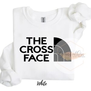 Pu&ograve; includere: Felpa bianca con testo nero che recita "THE CROSS FACE" e una grafica nera e grigia di una catena montuosa.