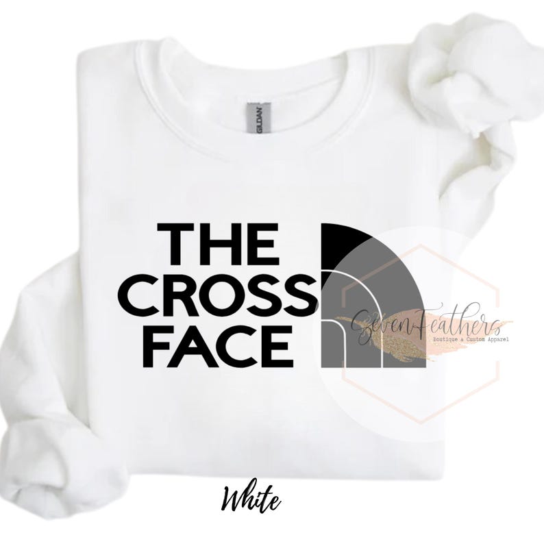Pu&ograve; includere: Felpa bianca con testo nero che recita "THE CROSS FACE" e una grafica nera e grigia di una catena montuosa.