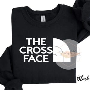 May include: Black sweatshirt with white text that reads "THE CROSS FACE" and a white graphic of a mountain range.