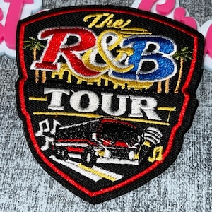 May include: Embroidered patch with a black background and a red border. The patch features the text "The R&B TOUR" in red, blue, and yellow. A graphic of a car and microphone is also included.