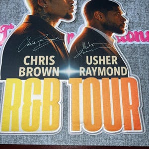 Könnte beinhalten: Dekoratives Bild mit Chris Brown und Usher Raymond. Das Bild enthält den Text "Chris Brown" und "Usher Raymond" mit ihren Unterschriften sowie den Text "RCB TOUR" in einem gelb-orangefarbenen Farbverlauf.