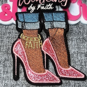 May include: An embroidered patch featuring two legs wearing blue cuffed jeans and pink glittery high-heeled shoes. A gold chain anklet with the word FAITH hangs on one ankle. Above the legs, the text reads Walking by Faith in pink script.