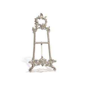May include: A silver metal easel with an ornate design. The easel is made of metal and has a decorative top.