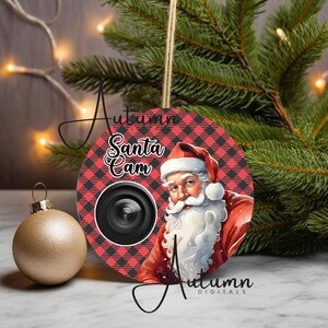 Op de afbeelding: Een rode en zwarte geruite kerstbal met een afbeelding van de kerstman en de tekst "Santa Cam".