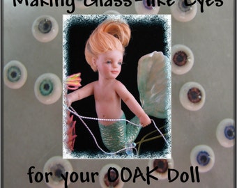 May include: A close-up of a mermaid doll with long, red hair and blue eyes. The doll is wearing a green tail and is holding a string of pearls. The image is titled "Making Glass-like Eyes for your OOAK Doll by Kori Leppert-Butts".