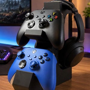 Puede incluir: Un soporte de juego negro que sostiene dos mandos inalámbricos y unos auriculares negros Sony. El mando superior es negro con botones multicolores, y el mando inferior es azul con botones negros y un logotipo de Xbox en el centro.