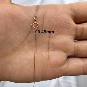 Könnte beinhalten: Nahaufnahme einer goldenen Kettenkette mit einem Karabinerverschluss. Die Kette ist 0,45 mm dick.