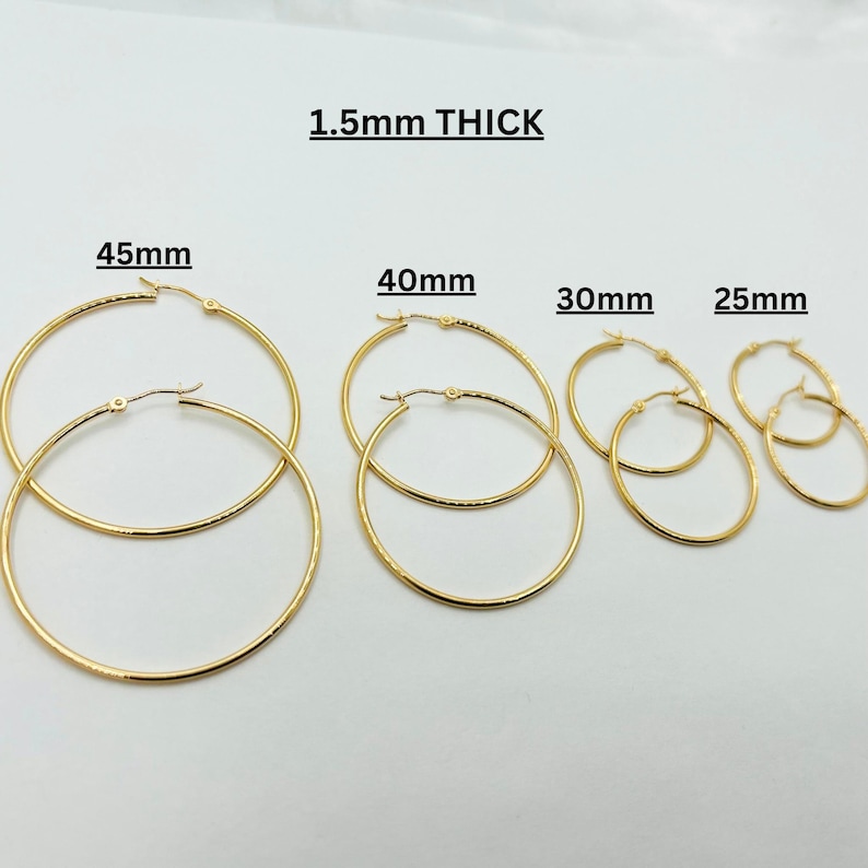 May include: Gold-colored hoop earrings in various sizes: 25mm, 30mm, 40mm, and 45mm. The text "1.5mm THICK" is displayed above the earrings. These earrings are a classic jewelry staple.