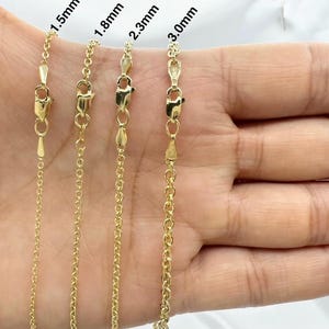 May include: Four gold chains of different thicknesses, 1.5mm, 1.8mm, 2.3mm, and 3.0mm, are displayed on a hand. The chains are all the same style, with a delicate, rounded link.