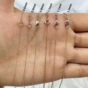 May include: A close-up of six gold chains of different thicknesses, ranging from 0.6mm to 1.3mm. The chains are laid out on a hand, with the thickness of each chain labeled.