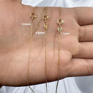May include: Three gold chains of different thicknesses, labeled 0.6mm, 0.8mm, and 1.1mm. The chains are laid out on a hand, showing the difference in thickness.