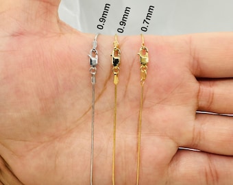 May include: Three silver and gold chains of different thicknesses, 0.9mm, 0.9mm, and 0.7mm, are displayed on a person's hand. The chains are all the same length and have a lobster clasp.