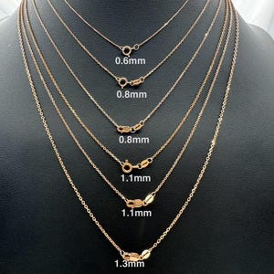 May include: Six gold chains of different thicknesses, hanging from a display stand. The chains are labeled with their thickness in millimeters: 0.6mm, 0.8mm, 0.8mm, 1.1mm, 1.1mm, and 1.3mm.